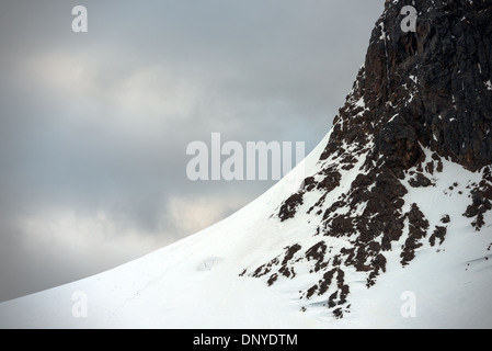 L'ANTARCTIQUE - une pente de neige et glace mène à une quasi-verticale d'une falaise rocheuse sur l'une des impressionnantes montagnes bordant la rive du Canal Lemaire dans l'Antarctique. Banque D'Images