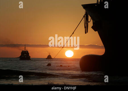 Jan 29, 2006 ; d'Ensenada, BC., Basse Californie, Mexique ; deux des remorqueurs travaillant 24 heures par jour, 7 jours par semaine pour libérer le porte-conteneurs APL Panama à partir de la plage de sable au sud de l'entrée du port dans la région de Ensenada, chugged dans le coucher du soleil le dimanche. Les remorqueurs tirer à leur plein pouvoir pendant les heures précédant et suivant la marée haute, puis réduire le pouvoir de maintenir leur Banque D'Images