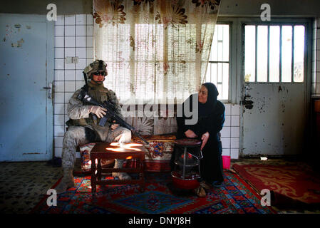 Jan 30, 2006 ; Al-Falujah, l'Iraq ; Lance Caporal Anthony Holdaway de Elmira, New York une compagnie maritime de l'Echo, 2e bataillon, 6ème Marines, RCT8, siège avec une femme dans la cuisine de sa maison. Les marines ont suspendu des patrouilles à pied dans la ville d'Al-Falujah (en raison de l'augmentation des morts) choisissant plutôt d'assurer temporairement l'homes de résidents d'utiliser comme postes d'observation. Banque D'Images