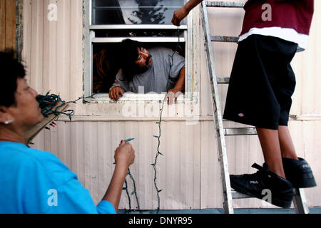 Feb 07, 2006 ; Pahokee, FL, USA ; Alejandra Rodriquez, de gauche, se bloque les lumières de Noël avec son beau-fils Juan Carlos Zavala, et petit-fils Pepe Jimenez à une fête de Noël organisée par Larry Wright, de Pahokee, pour les résidents d'Usher's Trailer Park à Pahokee mardi. Les résidents du parc étaient sans électricité pendant 101 jours après l'ouragan Wilma a frappé la région. Trois églises de t Banque D'Images