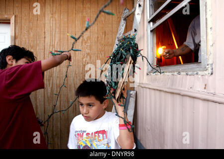 Feb 07, 2006 ; Pahokee, FL, USA ; Pepe Jimenez, de gauche, se bloque les lumières de Noël sur leur grand-mère, Alejandra Rodriquez, maison avec cousin Leonel Zavala , 11, et l'oncle Juan Carlos Zavala, à une fête de Noël organisée par Larry Wright, de Pahokee, pour les résidents d'Usher's Trailer Park à Pahokee mardi. Les résidents du parc étaient sans électricité pendant 101 jours après Hurrica Banque D'Images