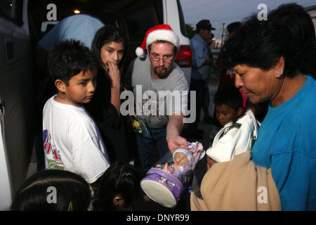 Feb 07, 2006 ; Pahokee, FL, USA ; Brett Smith, assistant pasteur à l'Église du Nazaréen à Pahokee, les mains des cadeaux aux résidents à une fête de Noël organisée par Larry Wright, de Pahokee, pour les familles d'Usher's Trailer Park à Pahokee mardi. Les résidents du parc étaient sans électricité pendant 101 jours après l'ouragan Wilma a frappé la région. Trois églises de l'espace a permis de pr Banque D'Images