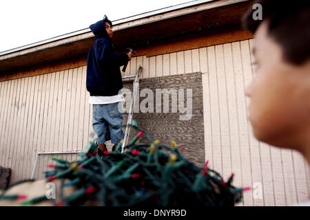 Feb 07, 2006 ; Pahokee, FL, USA ; Juan Carlos Zavala Jr., 14, à gauche, se bloque les lumières de Noël sur leur grand-mère, Alejandra Rodriguez, maison avec frère Leonel Zavala, 11, à une fête de Noël organisée par Larry Wright, de Pahokee, pour les résidents d'Usher's Trailer Park à Pahokee mardi. Les résidents du parc étaient sans électricité pendant 101 jours après l'ouragan Wilma a frappé le sont Banque D'Images