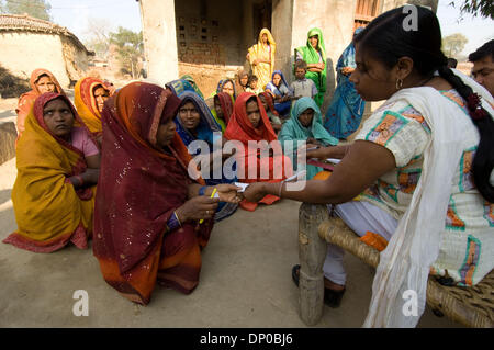 Mar 07, 2006 ; Anantpur Uttar-Pradesh, village, Inde ; un Micro-crédit CASHPOR employé, basant (homme assis avec la paperasse, un Centre Manager) collecte un bordereau de dépôt de banque, les chèques des clients, la participation à un dicsusses et problèmes sur sa visite hebdomadaire à un village éloigné où un groupe de clients qualifiés pour les micro-prêts. La femme assise à côté de Basant est Subnam, son superviseur (gestionnaire de Banque D'Images