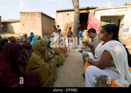 Mar 07, 2006 ; Anantpur Uttar-Pradesh, village, Inde ; un Micro-crédit CASHPOR employé, basant (homme assis avec la paperasse, un Centre Manager) collecte un bordereau de dépôt de banque, les chèques des clients, la participation à un dicsusses et problèmes sur sa visite hebdomadaire à un village éloigné où un groupe de clients qualifiés pour les micro-prêts. La femme assise à côté de Basant est Subnam, son superviseur (gestionnaire de Banque D'Images