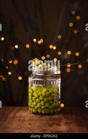 Ouvrir un bocal en verre de conserves de petits pois sur le fond sombre Banque D'Images