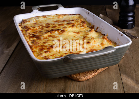 Lasagne dans un plat de service avec du fromage sur le dessus sur une vieille table en bois Banque D'Images