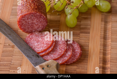 Libre de salami avec un couteau et un peu de raisin sur le côté Banque D'Images