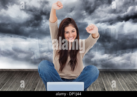 Image composite de femme regarde droit devant alors qu'elle célèbre en face de son ordinateur portable Banque D'Images