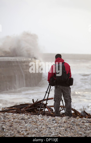 Un photographe prend des photos de l'hiver sur les vagues se briser s/n à Lyme Regis. Banque D'Images