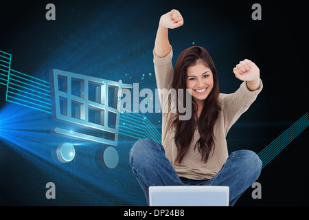 Image composite de femme regarde droit devant alors qu'elle célèbre en face de son ordinateur portable Banque D'Images