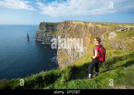 Walker sur le chemin des falaises de Moher, comté de Clare, Irlande. Banque D'Images