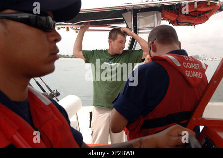 26 mai, 2006 ; Riviera Beach, FL, USA ; Jason Sullivan de West Palm Beach, (chemise verte), gratte la tête après avoir été intercepté par la Garde côtière BM3 Chris Stover, 23 ans, de Palm Beach Gardens (FN) Cory pompier Seale, 28 ans, de West Palm Beach, (non illustré), comme BM2 Chris Cowart, 23, un résident de West Palm Beach conserve deux bateaux pendant que Jason ralenti son bateau de pêche inspecté pour safet Banque D'Images