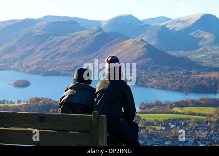 Jeune couple de marcheurs assis sur un banc au-dessus de la Derwent Water Lake District National Park avec la Northern Fells derrière Banque D'Images