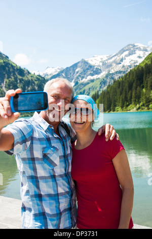 L'homme et de la femme mature de prendre une photo d'eux-mêmes, Woman Jogging in forest Lake, Autriche Banque D'Images