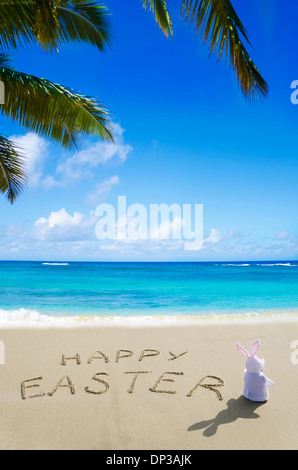 Panneau 'Joyeuses Pâques' avec bunny sur la plage de sable à l'océan Banque D'Images