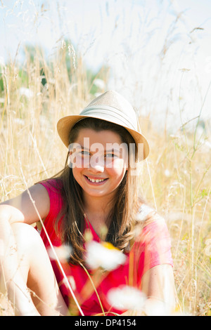 Portrait of Girl wearing hat, sitting in field and smiling at camera, Allemagne Banque D'Images