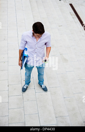 High angle view of young man standing outdoors, looking at cell phone, Allemagne Banque D'Images