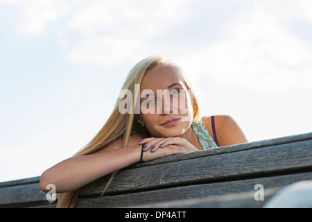 Portrait of teenage girl sitting on bench outdoors, looking at camera, Allemagne Banque D'Images