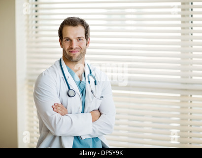 Jeune médecin homme debout les bras croisés Banque D'Images