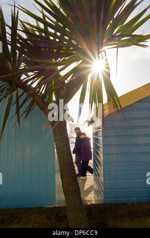 Personnes âgées en train de marcher le long de la promenade, pris entre deux cabines de plage. Banque D'Images