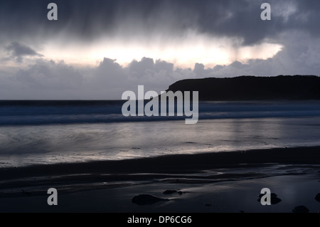 La pluie commence à tomber de sombres nuages reflétée sur la plage Banque D'Images