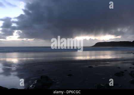 La pluie commence à tomber de sombres nuages reflétée sur la plage Banque D'Images