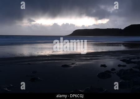 La pluie commence à tomber de sombres nuages reflétée sur la plage Banque D'Images