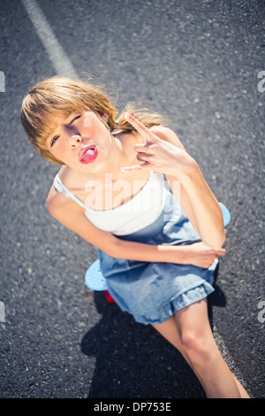 Trendy young woman making rock and roll hand gesture Banque D'Images