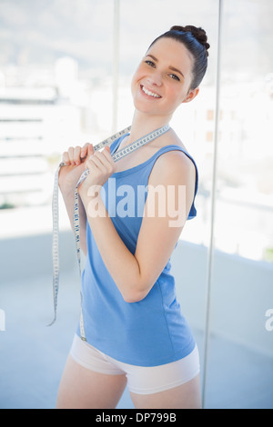 Cheerful gorgeous woman in sportswear holding measuring tape Banque D'Images