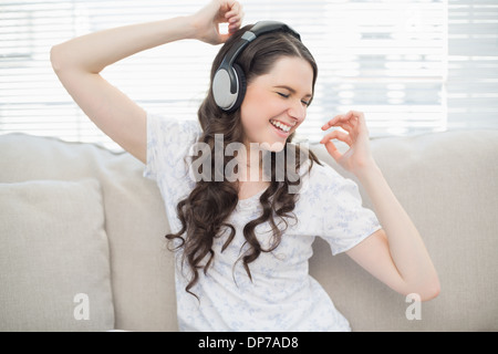 Souriante jeune femme danser tout en écoutant de la musique Banque D'Images