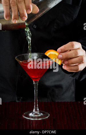 Professional bartender pouring cocktail rouge dans un verre à martini à Banque D'Images