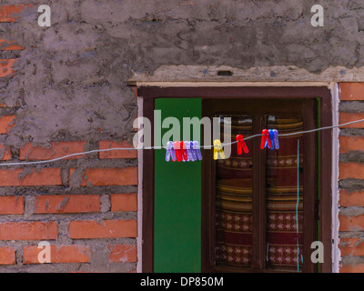 Pinces à linge en plastique coloré on clothes line en face d'une porte et mur de brique et de mortier dans les régions rurales de la Bolivie. Banque D'Images