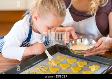 La cuisson avec la famille - Mère et fille coat self made cookies à l'aide d'un pinceau Banque D'Images