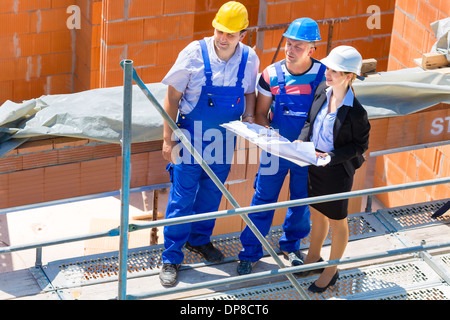 Ou l'équipe de l'architecte et le constructeur ou le travailleur avec des casques de discuter sur un plan de construction d'échafaudage ou plan directeur ou d'une liste de contrôle Banque D'Images