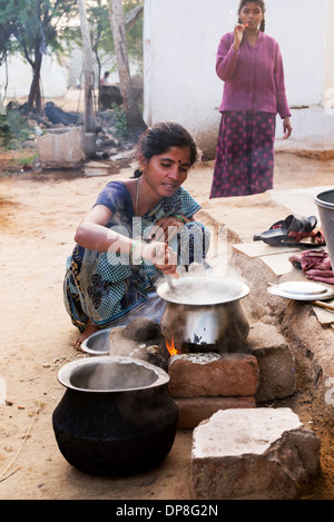 Femme indienne cuisson du riz sur un feu ouvert à l'extérieur de sa maison dans un village rural. L'Andhra Pradesh, Inde Banque D'Images