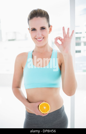 Smiling model in sportswear holding des tranches d'orange sur son ventre Banque D'Images