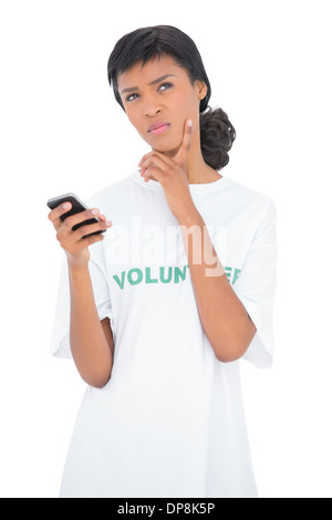 Thoughtful black haired volunteer holding a mobile phone Banque D'Images