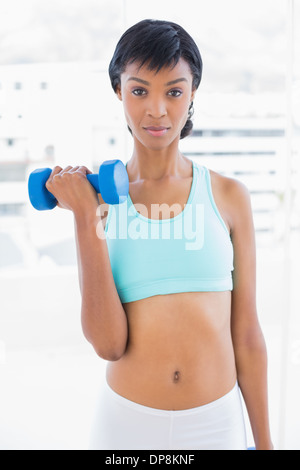 Stern black haired woman holding a dumbbell Banque D'Images