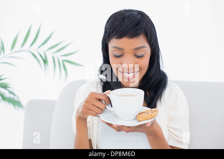 Femme aux cheveux noir détendue dans des vêtements blancs de boire du café Banque D'Images