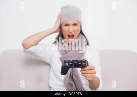 Brunette furieuse avec chapeau d'hiver sur les consoles de jeux vidéo Banque D'Images