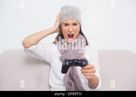 Brunette en colère avec chapeau d'hiver sur les consoles de jeux vidéo Banque D'Images