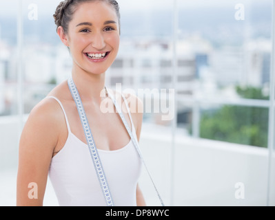 Cheerful sporty brunette holding measuring tape Banque D'Images