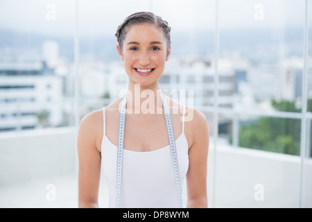 Happy sporty brunette holding measuring tape Banque D'Images