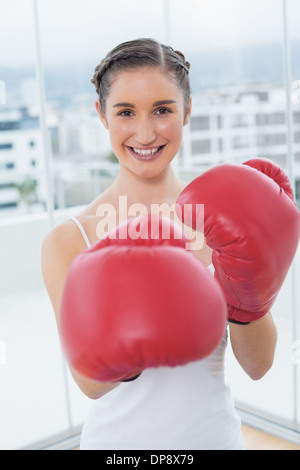 Cheerful sporty brunette wearing red boxing gloves Banque D'Images