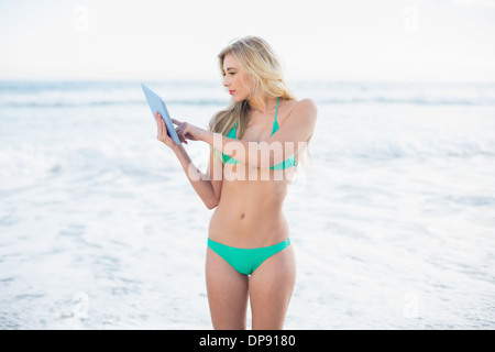 Femme blonde concentré en bikini vert à l'aide d'un tablet pc Banque D'Images