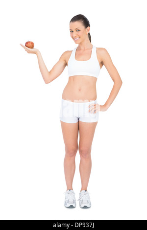 Smiling woman holding red apple looking at camera Banque D'Images