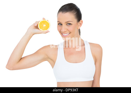 Happy woman in sportswear holding tranche d'orange. Banque D'Images