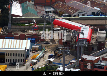 LA PAZ, BOLIVIE, le 9 janvier 2014. Un Eurocopter AS 350 B3 Ecureuil hélicoptère appartenant à la Force aérienne bolivienne (FAB) plane sur le bâtiment de la gare à côté du cimetière de La Paz comme il se prépare à effectuer un câble synthétique léger entre les pylônes de la nouvelle télécabine téléphérique / actuellement en construction pour relier les villes de El Alto et La Paz. C'est la première partie du processus d'installer le dernier câble en acier qui va transporter les gondoles. Trois lignes de tramway sont prévus dans le cadre d'un projet ambitieux pour réduire l'encombrement du trafic, avec la première ligne, qui doit être achevé d'ici mars 2014. Banque D'Images