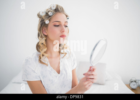 Blonde à la réflexion à détendue sur un lit confortable Banque D'Images